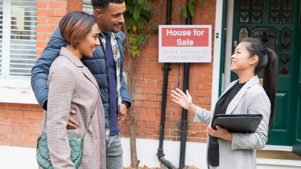 Real estate agent talking with couple outside house for sale