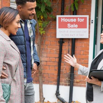 Real estate agent talking with couple outside house for sale