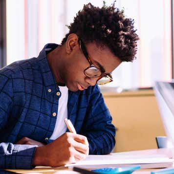 Man writing while sitting at table in library