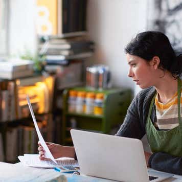Young female artist in studio working on laptop.
