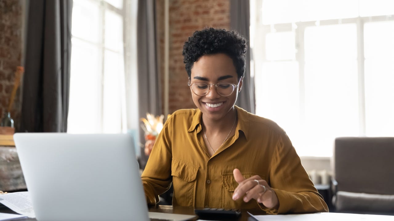 Happy young Afro American entrepreneur woman in glasses counting profit