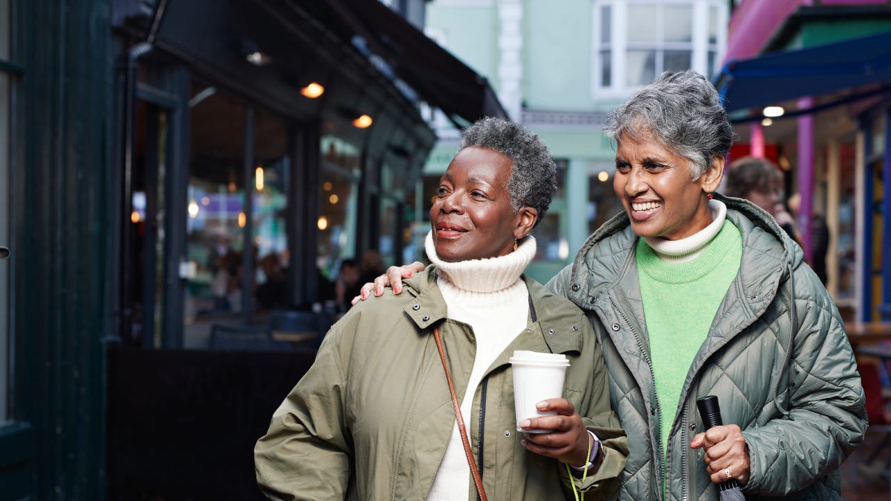 Happy elderly female friends looking away while walking in market