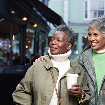 Happy elderly female friends looking away while walking in market