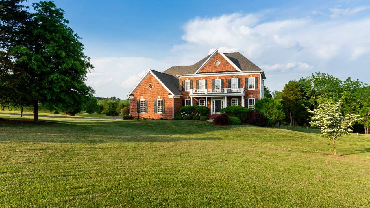 Front of home and garage of large single family modern US house with landscaped gardens and lawn on a warm sunny summers day