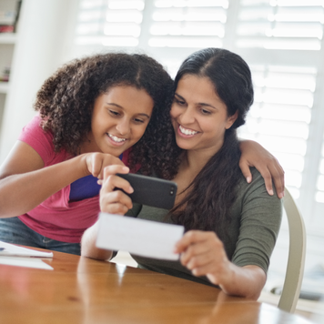Mother and daughter smiling at smartphone