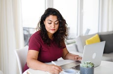 Portrait of young woman with laptop working indoors, home office concept.
