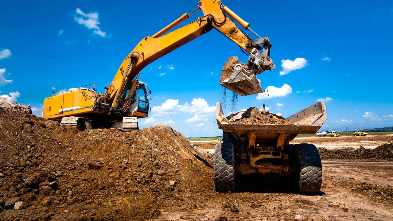 Industrial truck loader excavator moving earth and unloading into a dumper truck