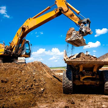 Industrial truck loader excavator moving earth and unloading into a dumper truck