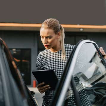 Female used car dealer checking vehicle before customer