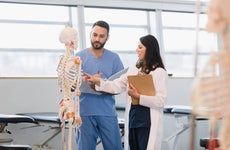 A young adult male medical student works one-on-one with his mid adult female professor.