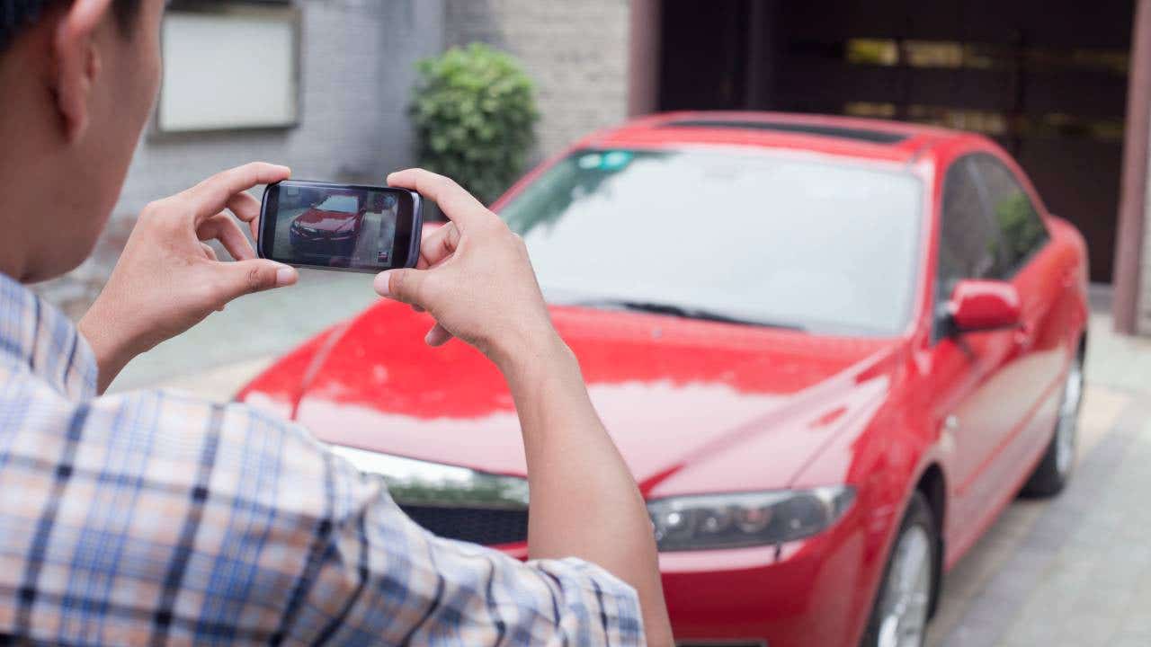 Young Man Taking a Picture of His Car