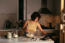 Kitchen activities: a young woman making sourdough bread at home while watching a live baking session online.