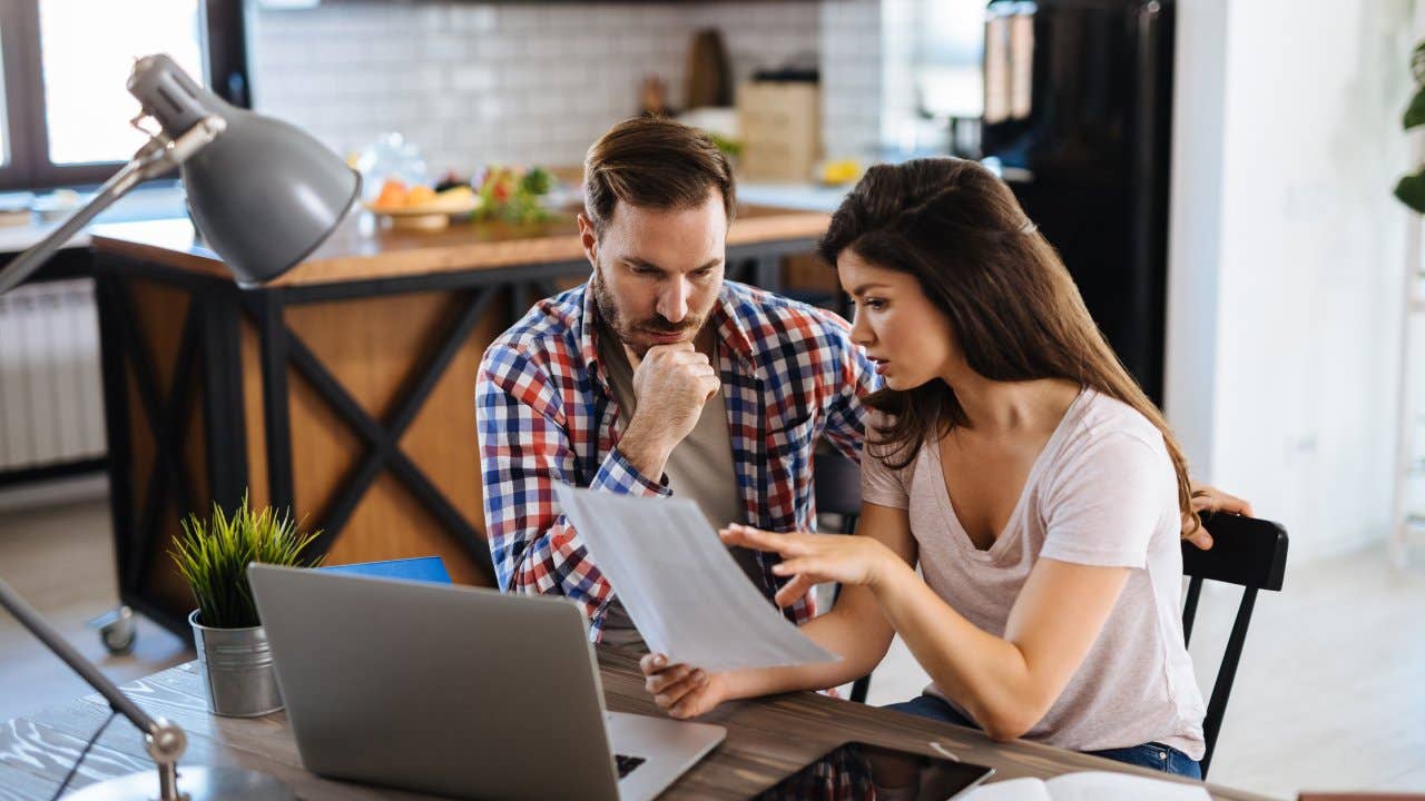 Frustrated couple checking bills at home using laptop