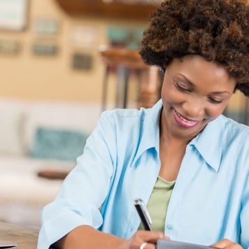 A middle aged adult woman happily balancing her checkbook