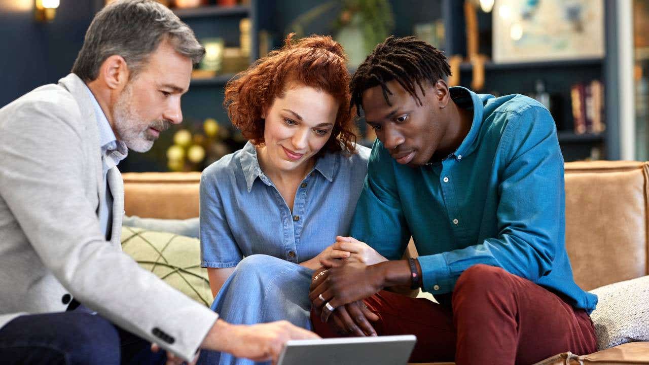 Mature financial advisor planning investment with multi-ethnic couple at office.