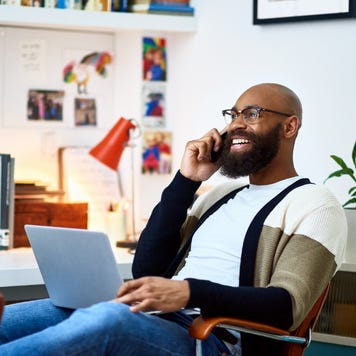 A Black image owner smiles while chatting on the phone in his office