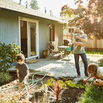 Family watering garden in backyard on summer morning