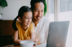 Happy father and young daughter on laptop video call at home, Tokyo