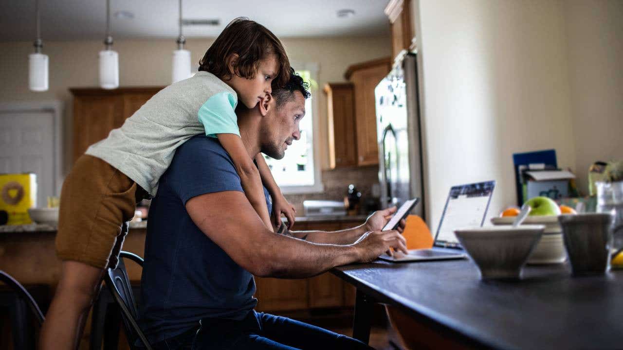 Father using laptop while son looks over his shoulder