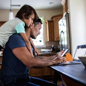 Father using laptop while son looks over his shoulder
