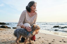 Woman with yorkshire dog on the beach at sunset