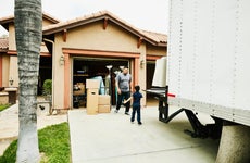Young son helping father move items from moving truck into new house