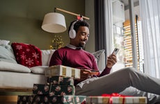 African American man sitting on the floor, using a credit card and smart phone. He is doing online Christmas shopping.
