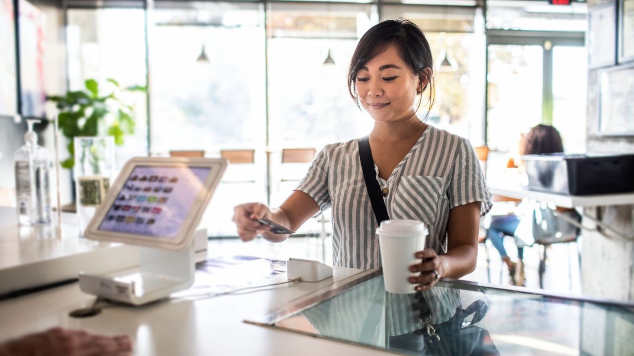 Young woman using credit card reader at coffee shop counter