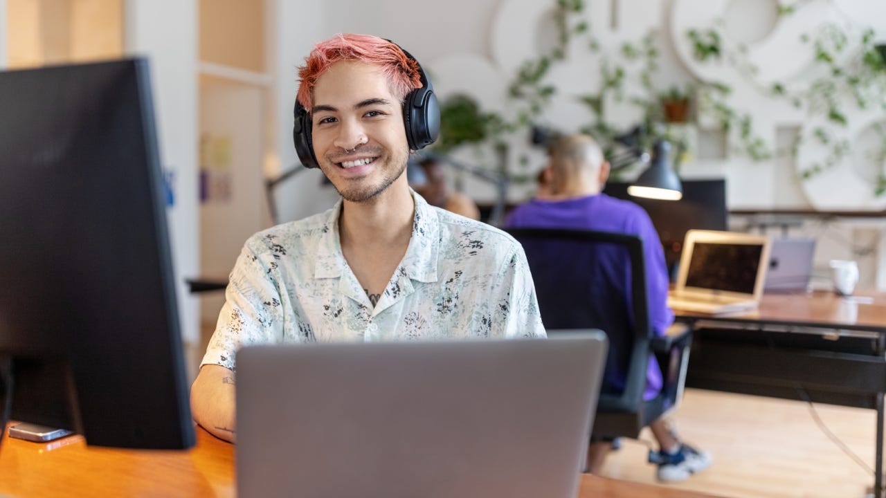 Happy young professional smiling and looking up from their computer