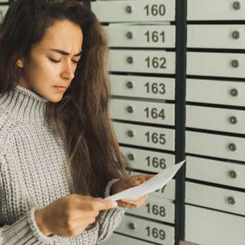 Upset and stressed woman near post box disappointed by bad news and bills from letter mail