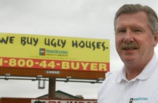 Paul Parker of HomeVestors by one of the many signs the company has put up in the Denver Metro area
