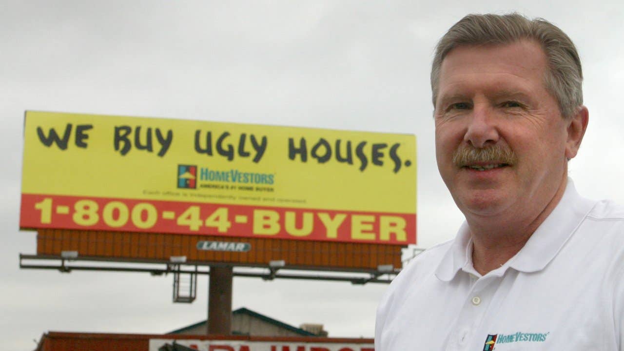 Paul Parker of HomeVestors by one of the many signs the company has put up in the Denver Metro area