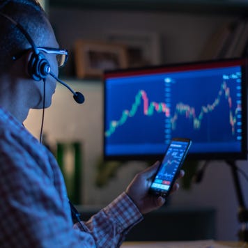 Man looking at currency trading app on his smart phone from his home office