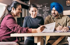 A Sikh man and woman review documents with a loan officer.