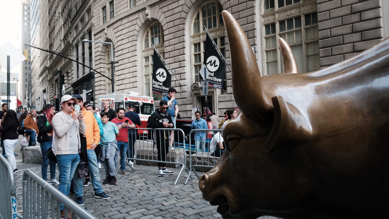 People pose by the New York stock market bull statue