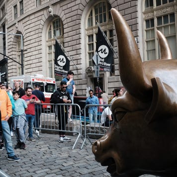 People pose by the New York stock market bull statue