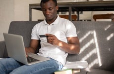 African American student shopping online sitting on sofa - stock photo