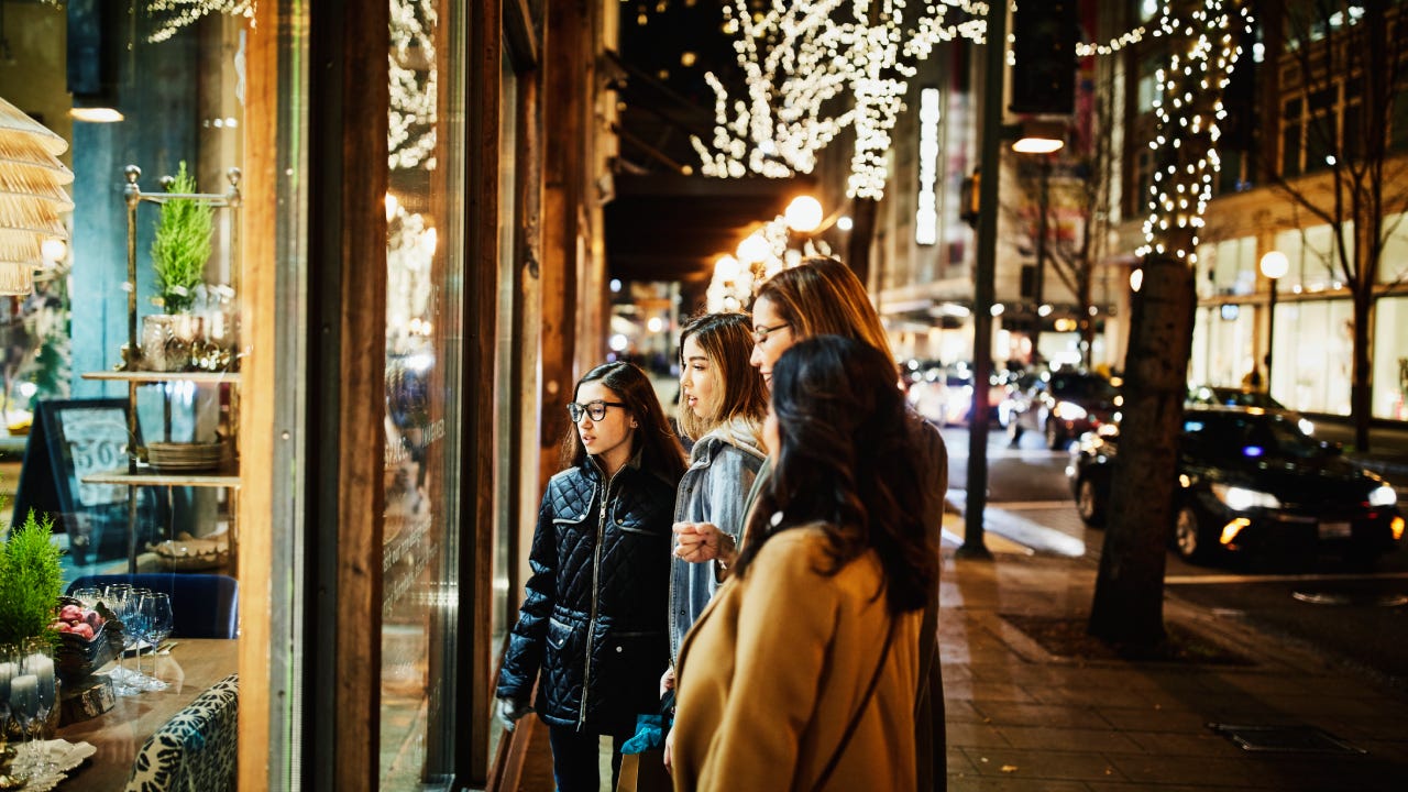 Two mature women and teenage daughters window shopping during holidays - stock photo