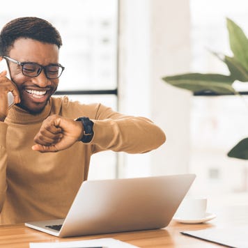 Happy guy looking at watch talking on phon