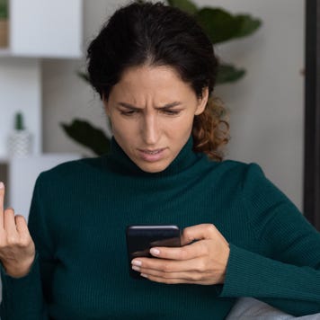 Concerned lady looking on smartphone having finance stolen from card