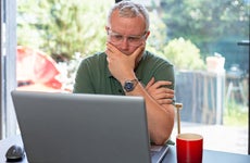 Worried man looking at laptop in modern home interior