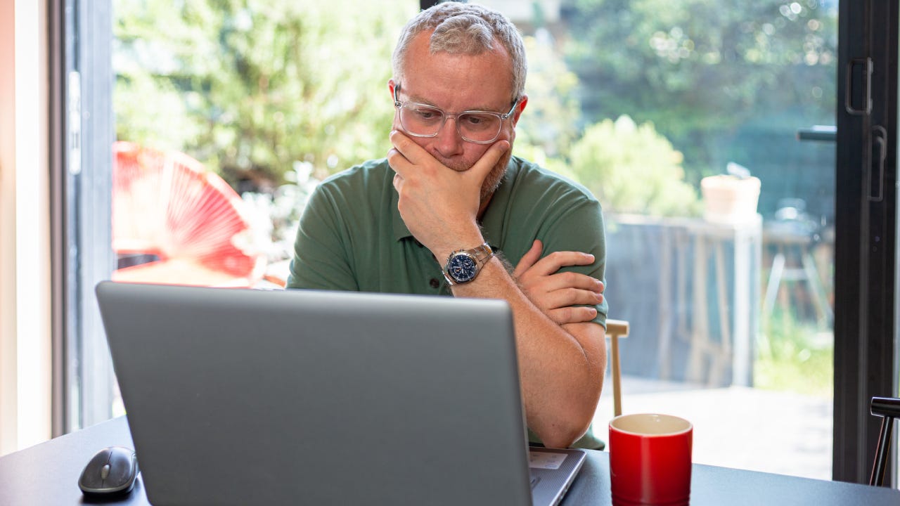 Worried man looking at laptop in modern home interior