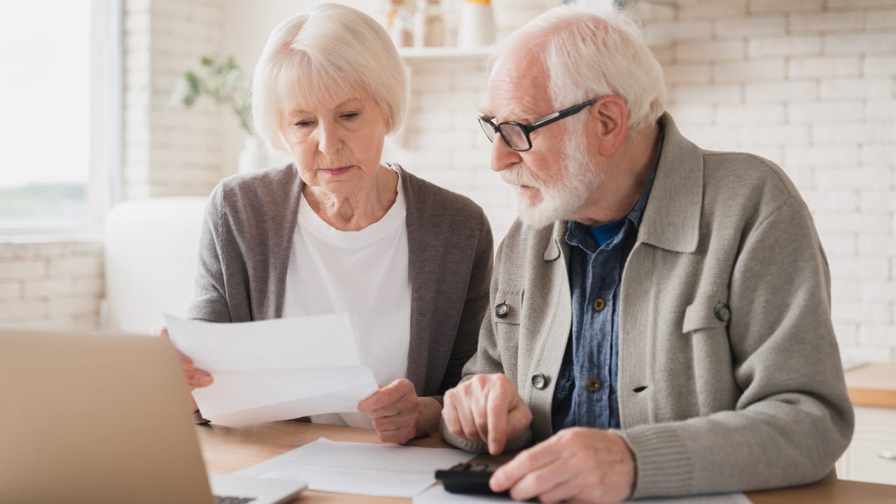 Elderly couple seriously reviewing financial documents