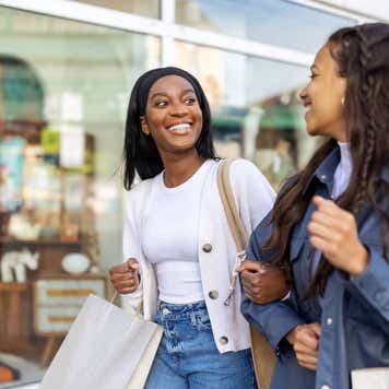 Two women friends with shopping bags walking in the city