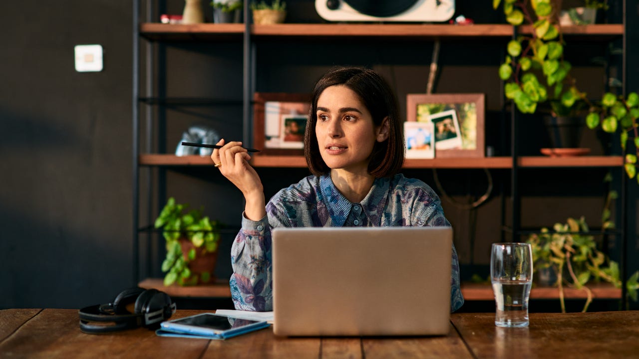 Woman sitting at a desk in front of a grey laptop