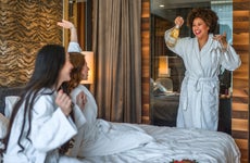 Cheerful young women celebrating with champagne in a bedroom.