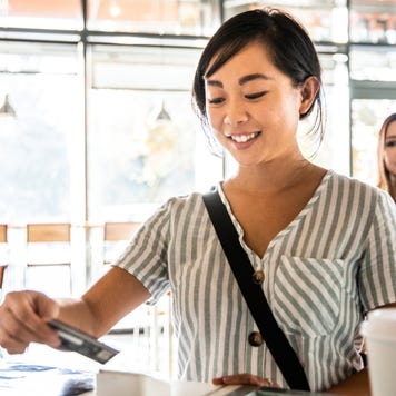 Young woman using credit card reader at coffee shop counter