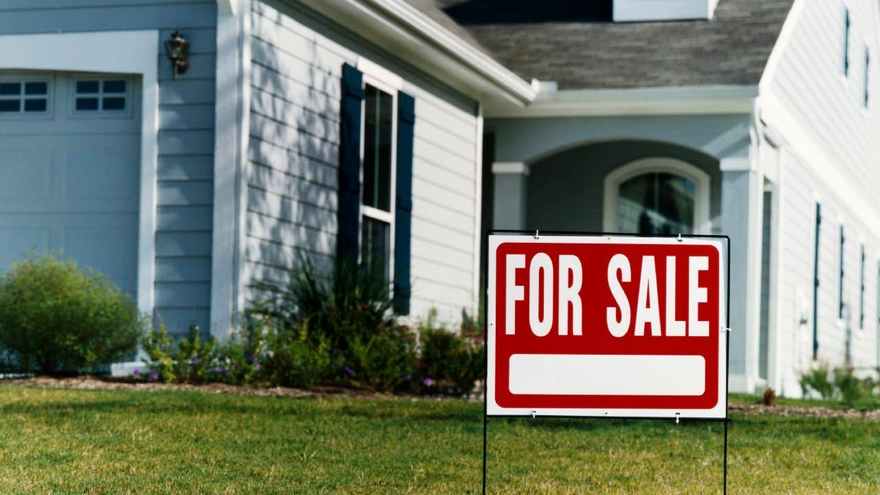 "For Sale" sign located on the front lawn of a home
