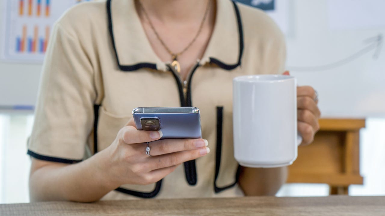 Woman holding a cellphone and drinking coffee