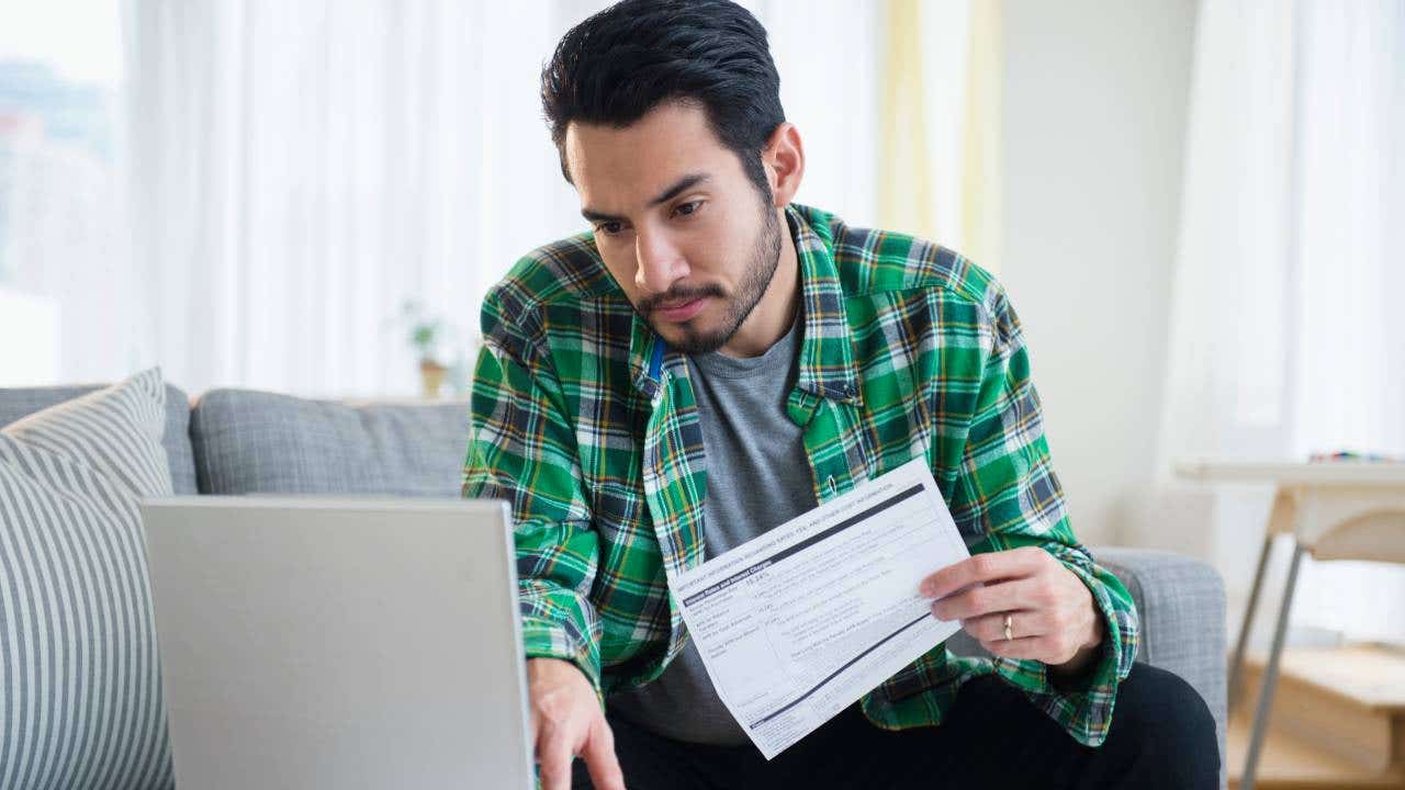 Mixed race man paying bills in living room